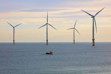 Small Fishing Boat dwarfed by huge Wind Turbines off the North East Coast, Redcar, North Yorkshire,...