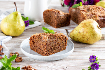 Piece of homemade chocolate cake with pears and chocolate on a wooden background