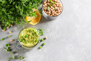 Hummus. Glass jar of homemade hummus garnished with chickpeas and green peas, olive oil. Flat lay, middle east food, vegetarian snack. Copy space