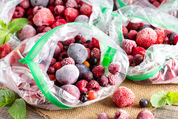 Frozen berries: black currant, red currant, blackberry, blueberry, raspberry, strawberry, cherry, plum in a plastic bag on a table. Frozen food.