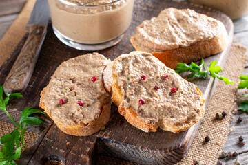Fresh homemade chicken liver pate on bread on rustic background