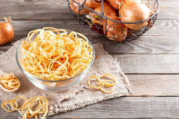 Dried onion rings in a glass bowl on a table. Spices and food ingredients. Copy space