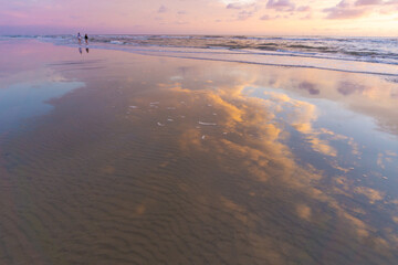 Beautiful colors at sunset on the Dutch coast. 2 unknown women walking through the water.
