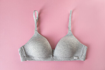 Gray organic or recycled cotton bra on pastel pink background, top view, copy space, flat lay. Concept of femininity, comfort, home clothes, underwear, natural textile, minimal style. Horizontal
