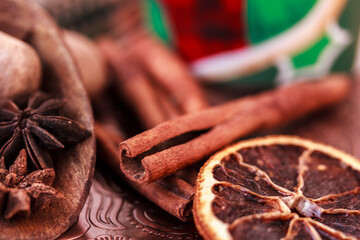 Cinnamon sticks, star anise, dried orange, nutmeg  in a wooden scoop on brown metal background...