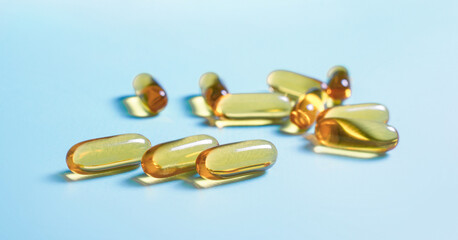 Oil capsules, vitamins on blue background.