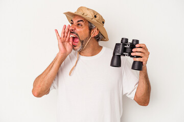 Middle age caucasian man holding binoculars isolated on white background  shouting and holding palm near opened mouth.