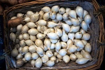 Small white onion seedlings in a wicker basket for sale in the market