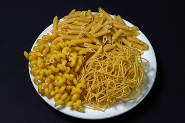 Raw pasta on a black background. Different varieties of pasta. Italian cuisine concept