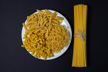 Raw pasta on a black background. Different varieties of pasta. Italian cuisine concept