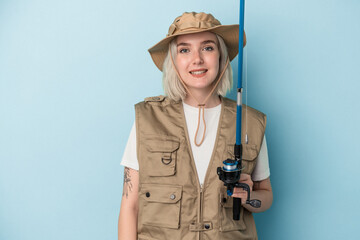 Young caucasian fisherwoman holding a rod isolated on blue background happy, smiling and cheerful.