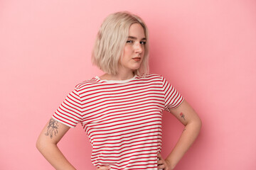 Young caucasian woman isolated on pink background frowning face in displeasure, keeps arms folded.