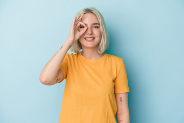 Young caucasian woman isolated on blue background excited keeping ok gesture on eye.