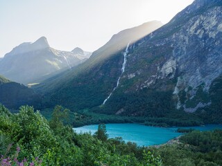 Naklejka na ściany i meble Waterfall between mountains with Lovatnet lake near Bodalsbreen glacier in Norway