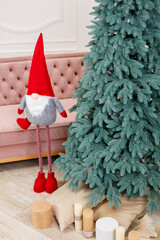 Obraz premium Christmas tree close-up without toys. Red toy elf gnome near the Christmas tree. Good New Year spirit.