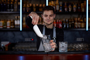 Barman puts the ice cubes into a glass