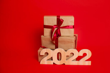 Merry Christmas and Happy New Year. Gift boxes and wooden numerals 2022 on a red background. A place for text.