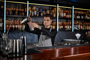 barman is making cocktail with steel shaker