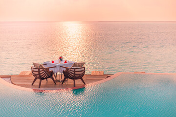 Seascape view under sunset light with dining table with infinity pool around. Romantic tropical getaway for two, couple concept. Chairs, food and romance. Luxury destination dining, honeymoon template
