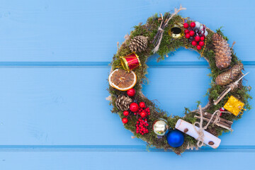 Christmas wreath hangs on a blue wooden wall