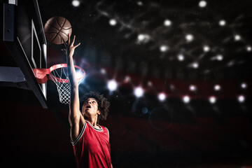 Basketball player in red uniform jumping high to make a slam dunk to the basket