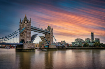 Naklejka premium Long exposure view of the lifted Tower Bridge in London with a ship passing by during sunset time