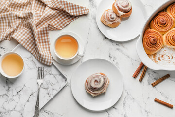 Tasty cinnamon rolls with tea on white background