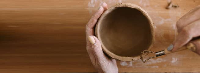 pottery in workshop clay art concept. close-up on the hands of a young ceramist with an unbaked...