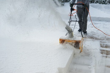 Man with machine removing snow in yard