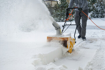 Man with machine removing snow in yard
