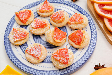 Plate with tasty grapefruit cookies on light wooden background, closeup