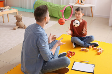 Male psychologist working with little boy in office. Autism concept