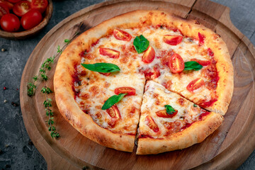 Baked pizza margarita with tomatoes and basil on a wooden board. Classic Italian Pizza