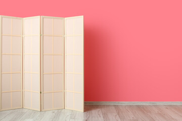 Light folding screen near pink wall
