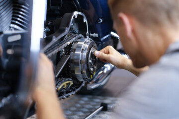 Mechanic repairs motorcycle engine in workshop closeup
