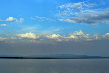 Beautiful sunset sky with clouds over Lake Baikal, Russia. View from the Peninsula Holy Nose. Summer. Beautiful evening sky with multi-colored bright clouds.