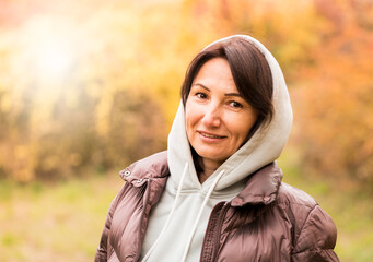 Nice peaceful middle aged woman smiling at camera on autumn day