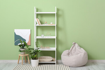 Stylish interior of living room with shelf unit, houseplants and beanbag chair near color wall