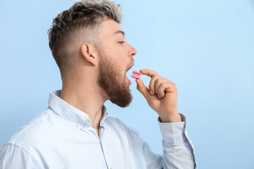Young man with chewing gum on color background - obrazy, fototapety, plakaty