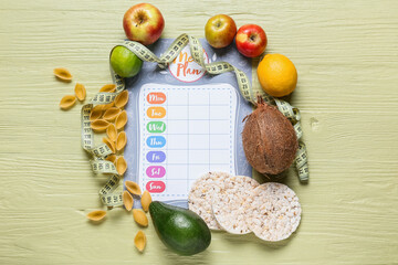 Meal plan with rice crackers, healthy products and measuring tape on color wooden background