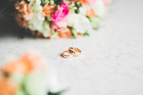 Beautiful toned picture with wedding rings against the background of a  bouquet of flowers Stock Photo | Adobe Stock