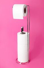 Holder with toilet paper rolls on color background