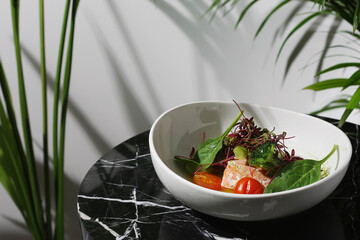 salmon steak with spinach on whute plate and marble table closeup