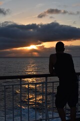 Fototapeta premium A young man looking the sunset from a boat