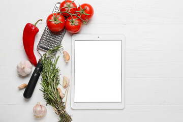 Digital recipe book, grater and different ingredients on white wooden background