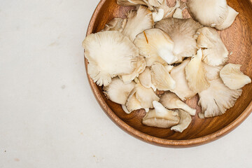 oyster mushrooms on a wooden bowl on a marble surface with copy space