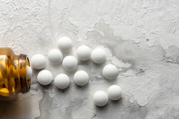 A handful of pills scattered on the table. A vial of medicines. Marble surface. Medicines. Stop COVID.