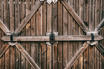 old wooden gate with hanging big black iron barn lock, selective focus