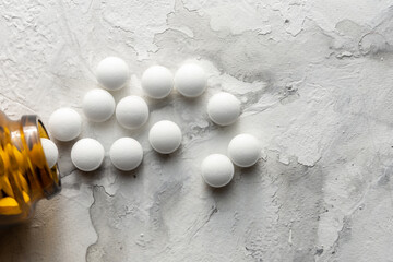 A handful of pills scattered on the table. A vial of medicines. Marble surface. Medicines. Stop COVID.