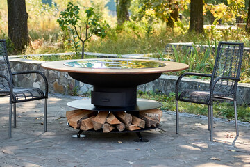 Kettle Grill Pit with Cast Iron Grid with flames . Round table-cooking surface. Hot BBQ on Backyard